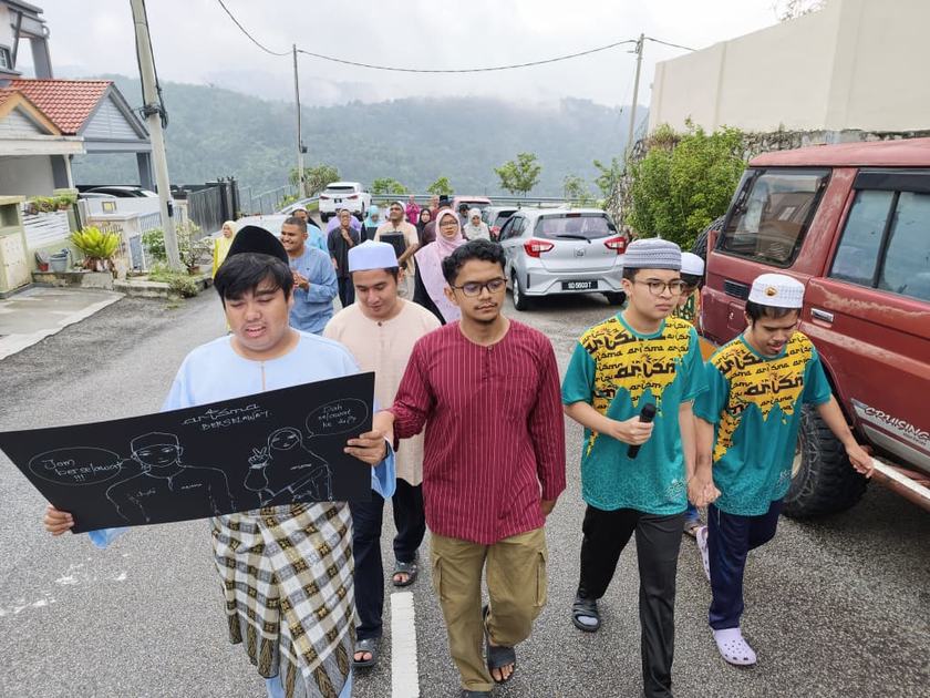 Perarakan berselawat pelatih ARISMA membawa papan tanda, dengan latar bukit di Ukay Perdana.